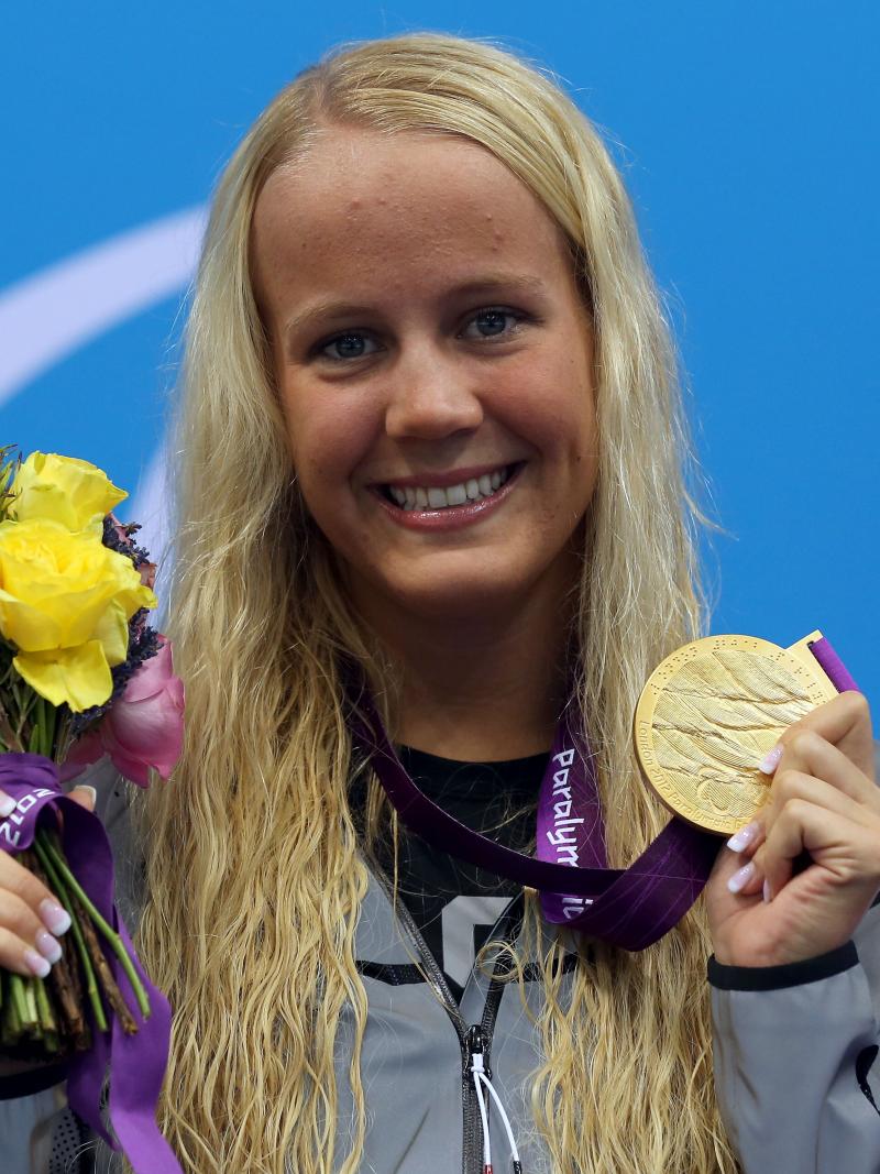 A picture foa a blonde woman showing her gold medal hanging around her neck