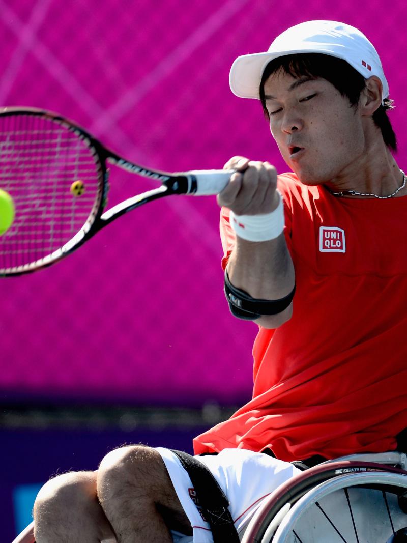 A picture of man in a wheelchair playing a forehand in a tennis match