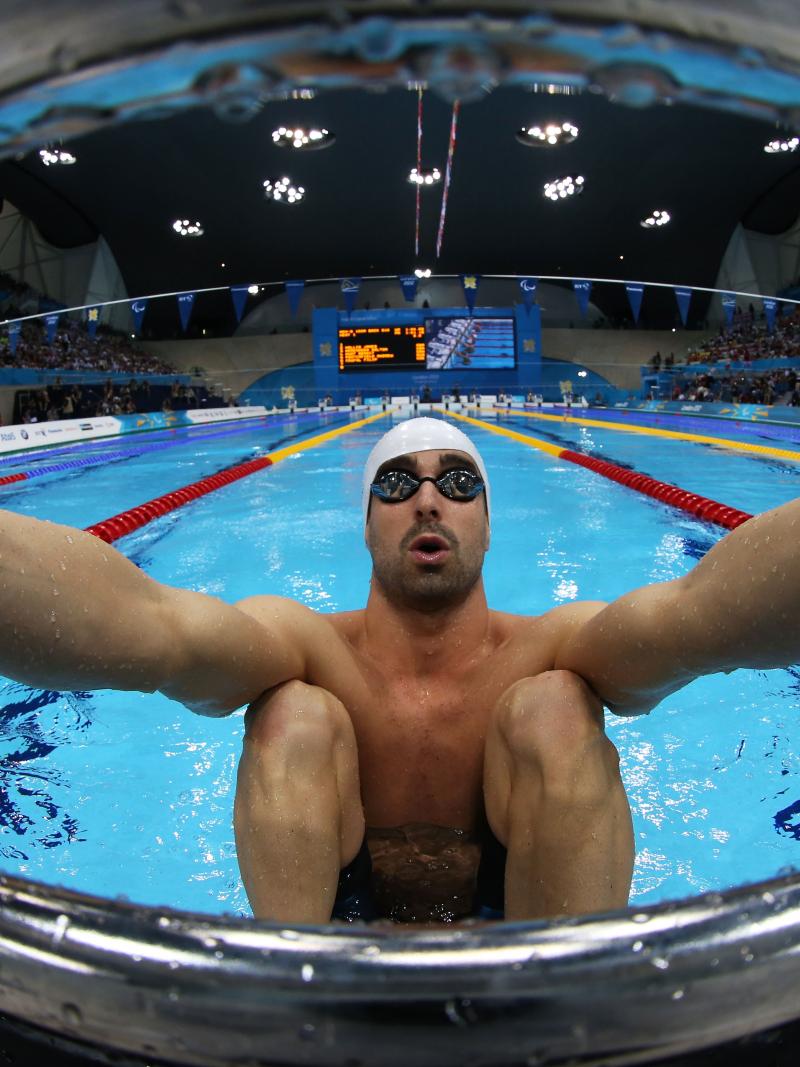 A picure of a man in the pool holding starting block with his hands