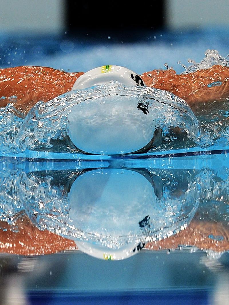 A picture of a man swimming with his both hands above the surface