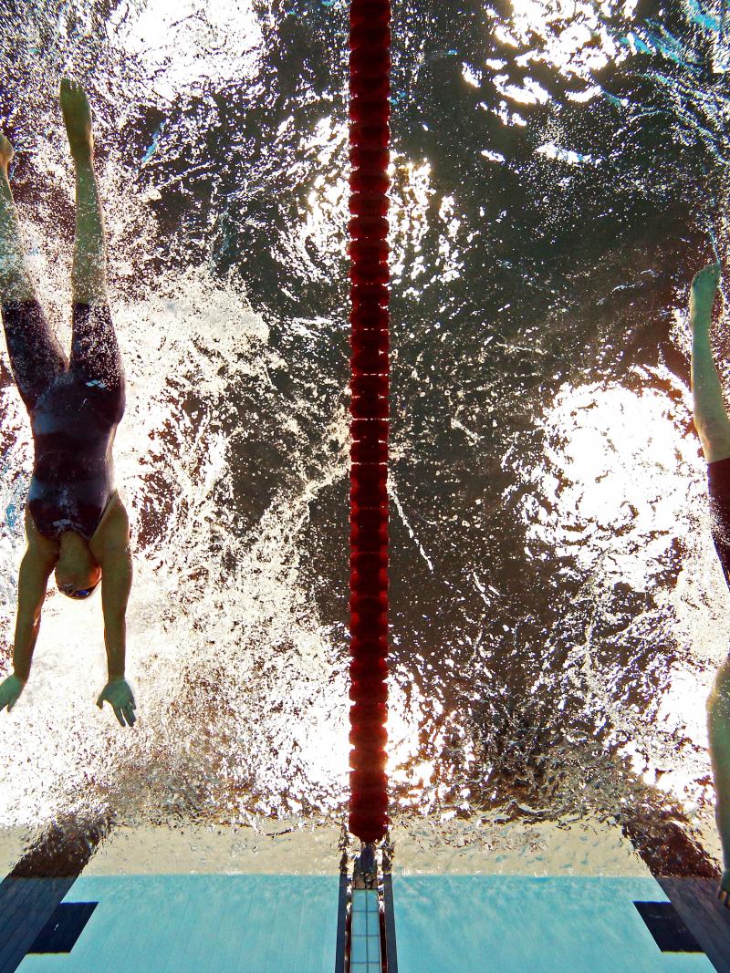 A picture of women in the pool touching the wall with their hands