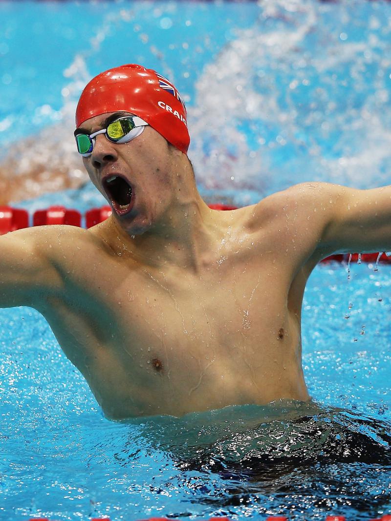 A picture of a man in the pool holding his hand up with clenched fist