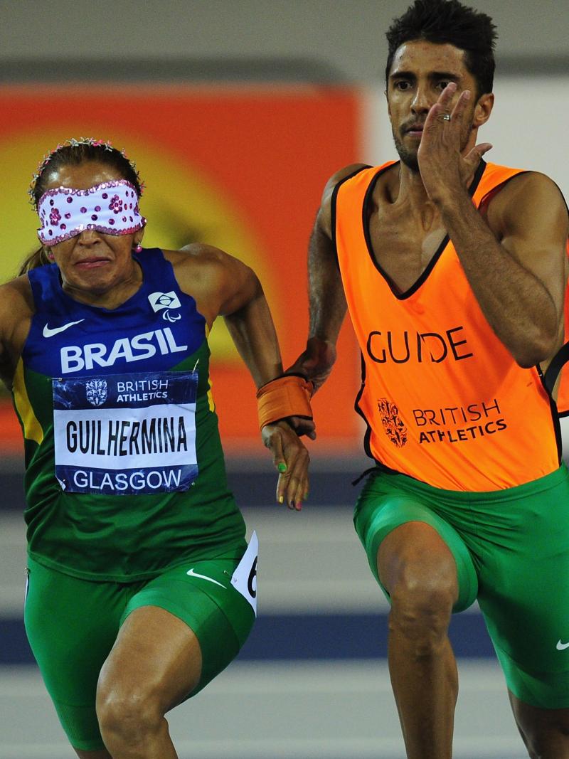 A picture of a blind woman running with her guide during an athletics race.