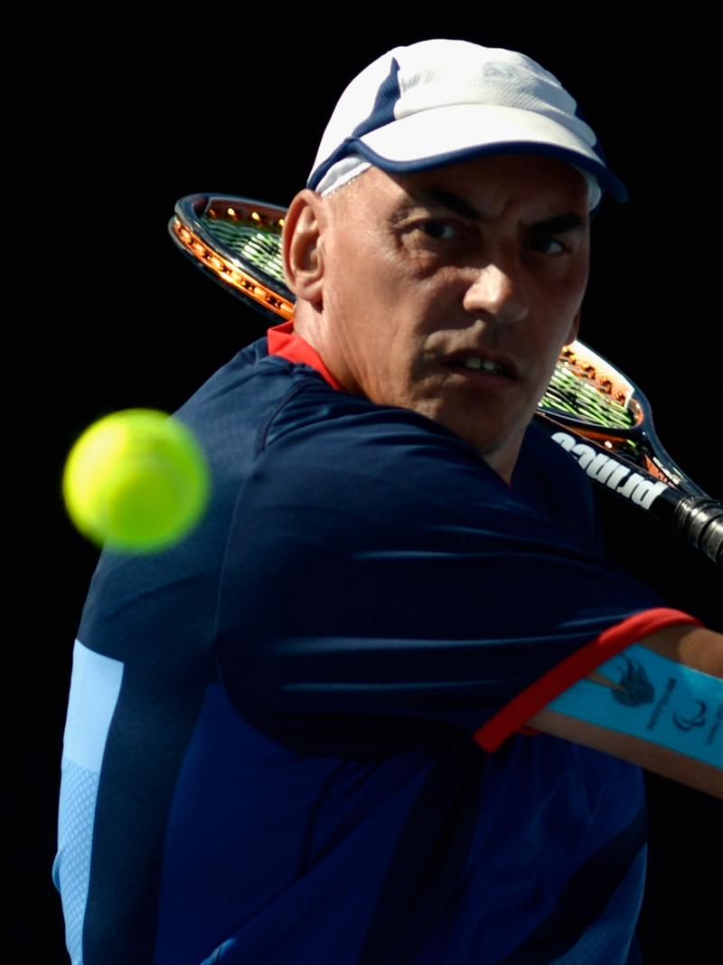 A picture of a man in a wheelchair playing a backhand during a wheelchair tennis match