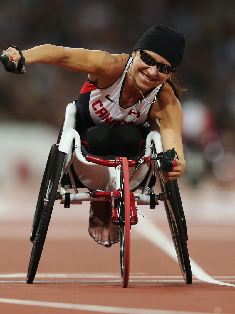 A picture of a woman in the wheelchair on a track celebrating the victory with her hand up