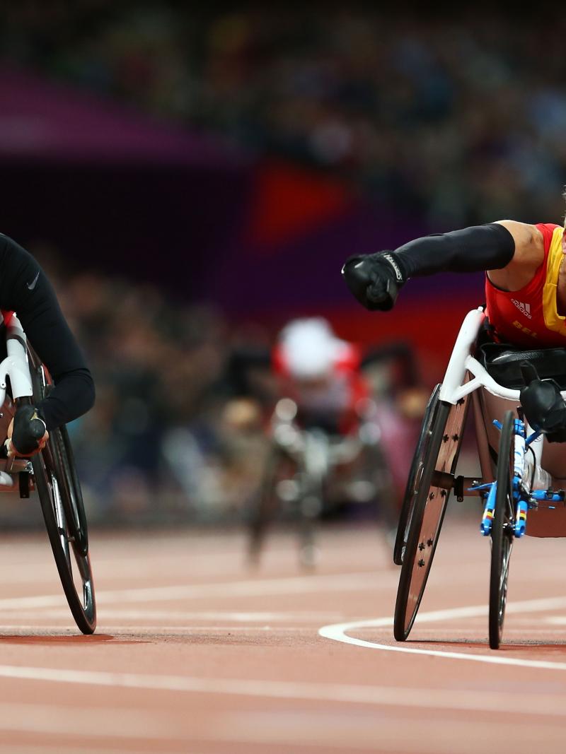 A picture of a woman in the wheelchair celebrating the victory with her hand up