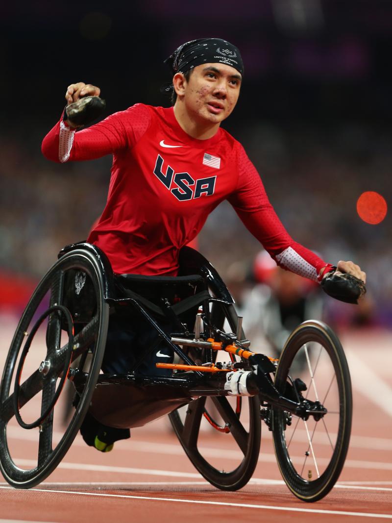 A picture of a man in a wheelchair celebrates after crossing a finish line