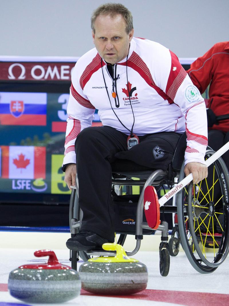 A picture of 2 mens in wheelchairs playing curling