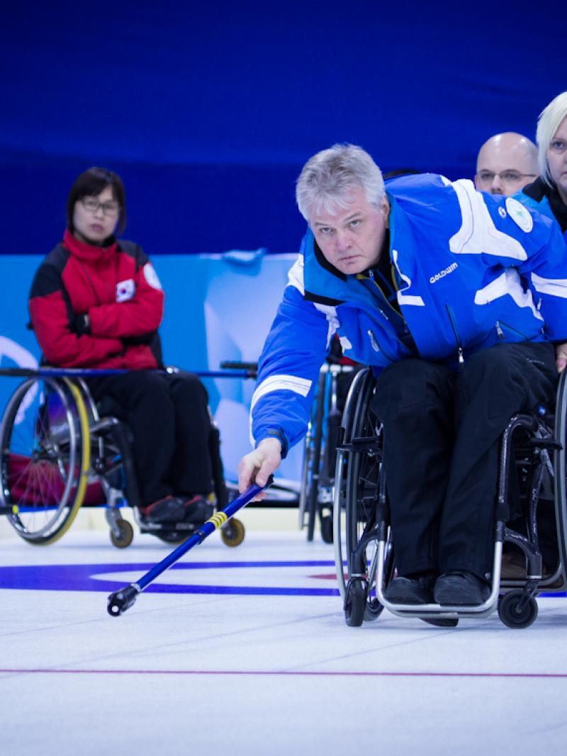 A picture of a man in a wheelchair playing curling