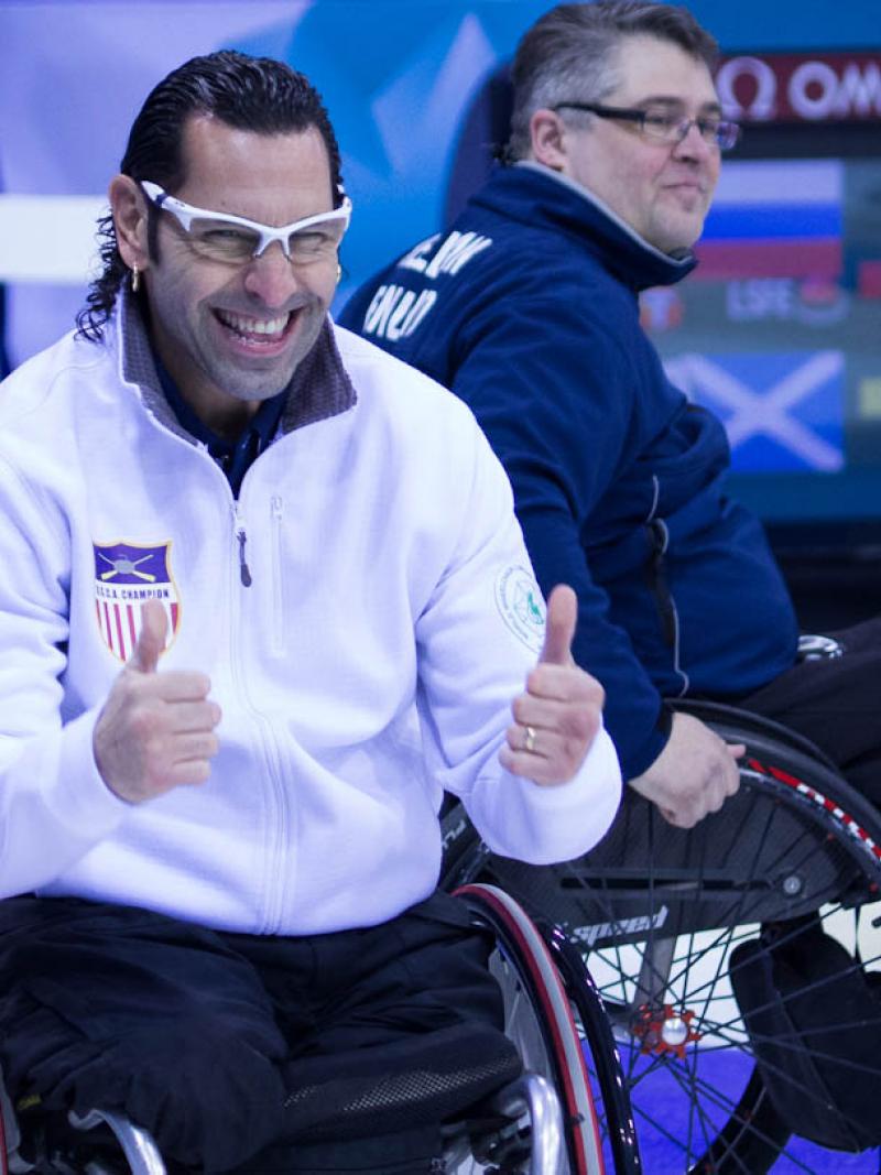 A picture of a man in a wheelchair tumbs up celebrating his victory