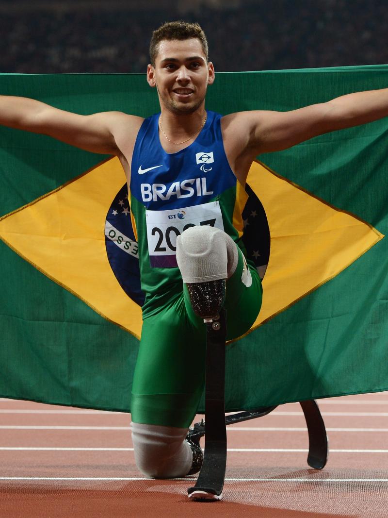 A picture of a man on the track posing with Brazilian flag in his hands
