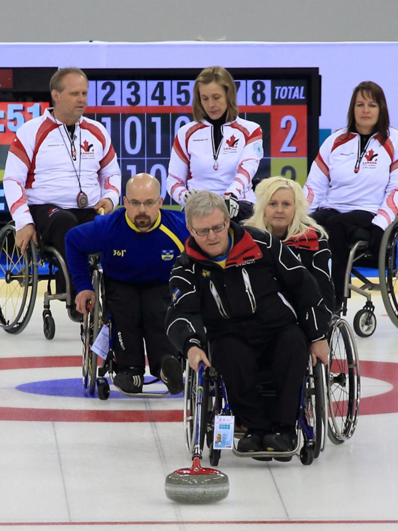 A picture of person in wheelchairs playing curling