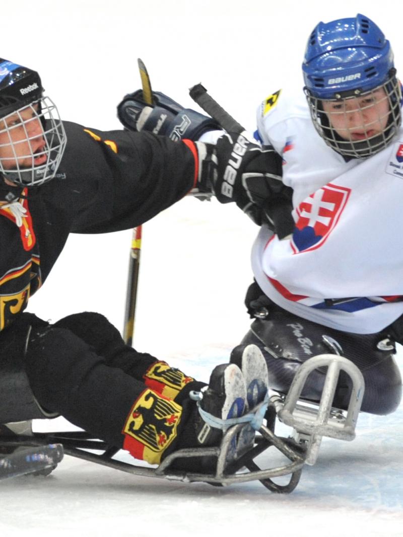 A picture of two men in sledge playing ice hockey