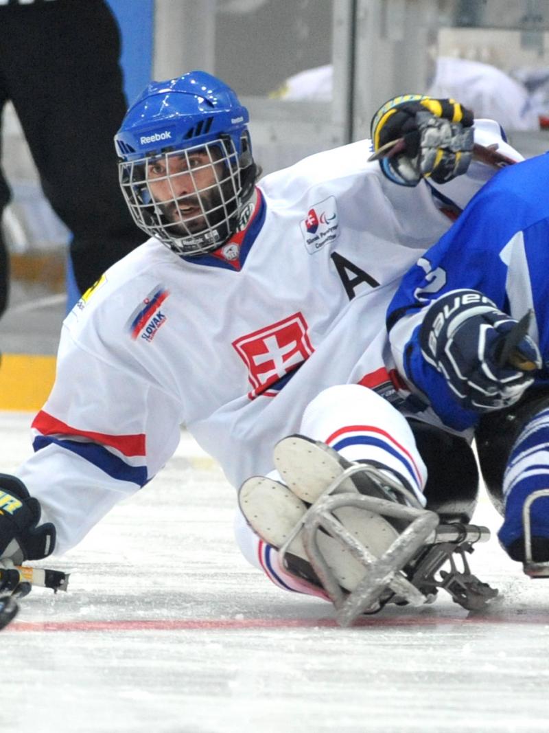 A picture of 2 men in sledge fighting the puck during a ice hockey match