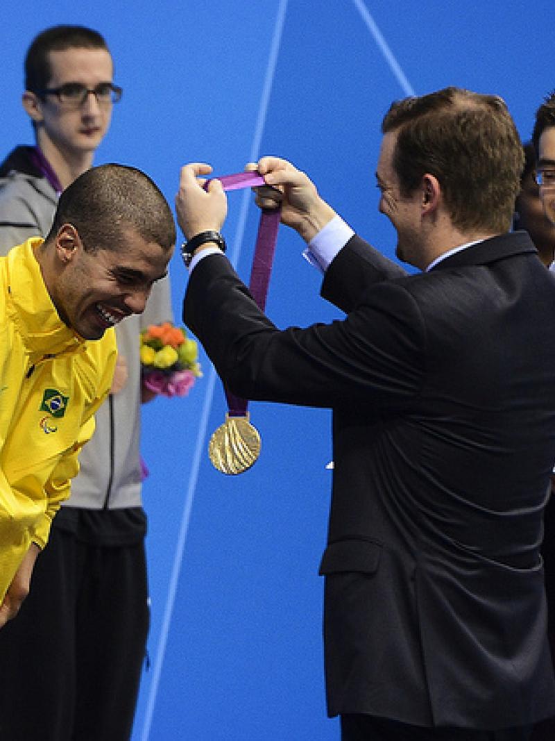 A picture of a man giving a medal to an athlete during a medal ceremony