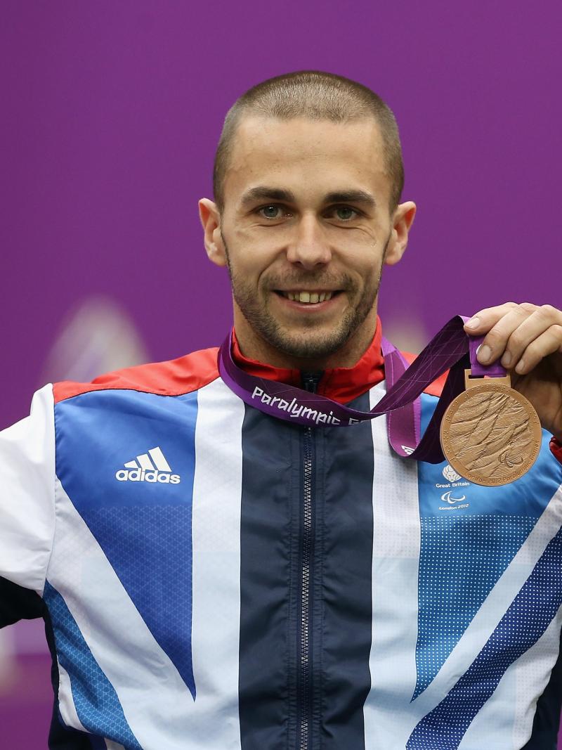 A picture of a man on a podium with a medal around his neck