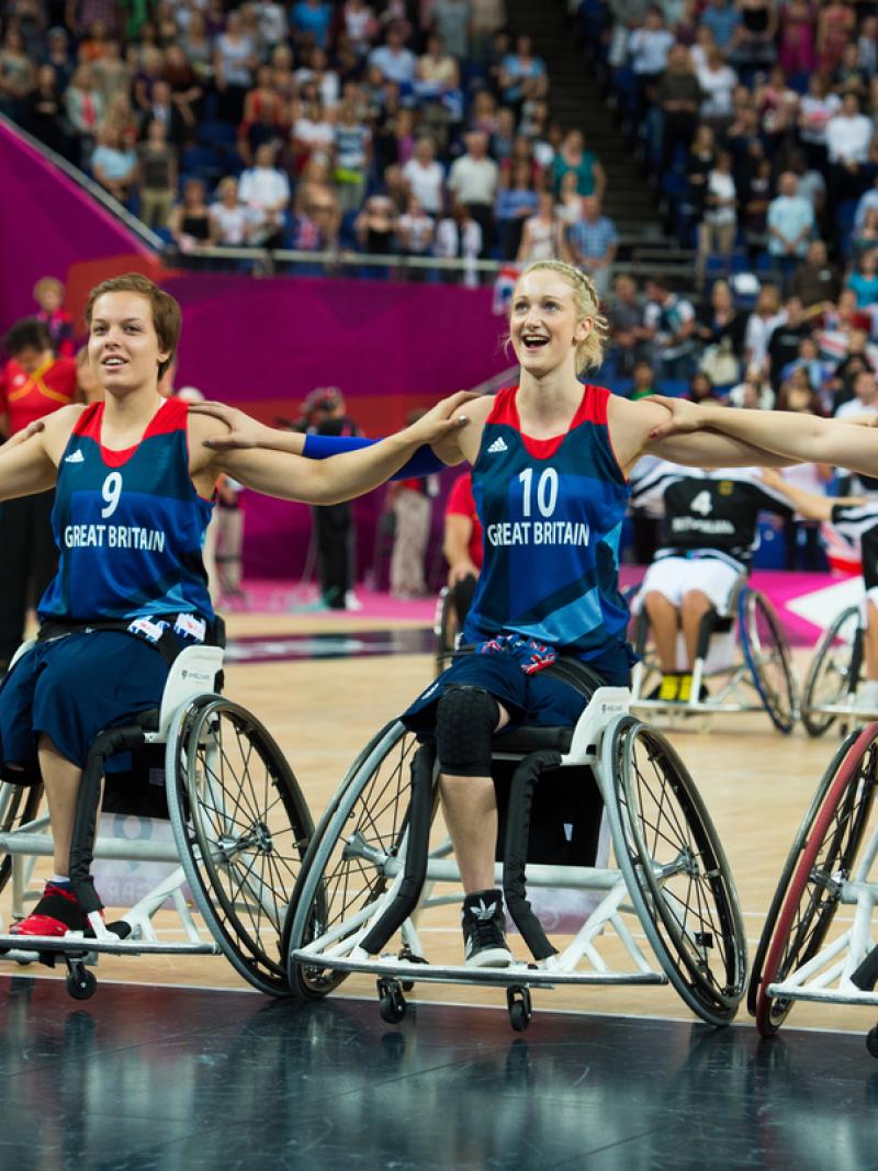 A picture of women in wheelchair posing for a group picture during a wheelchair basketball match