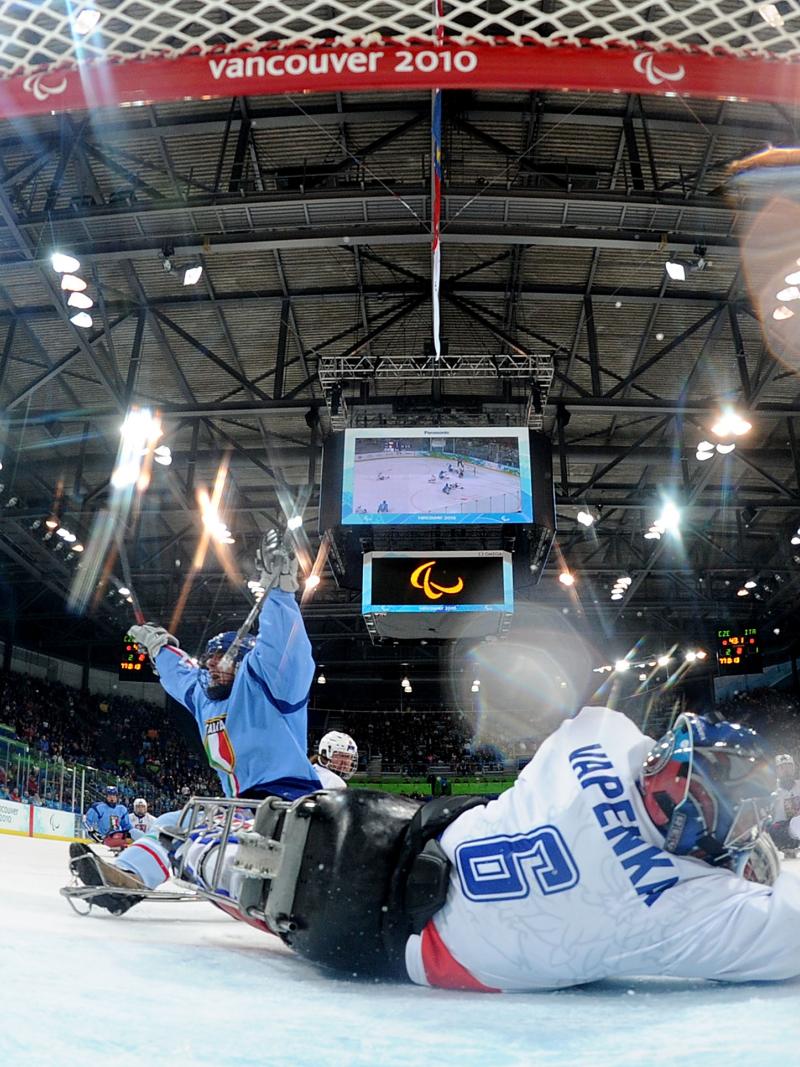 A picture of a man in a sledge celebrating his goal during an ice sledge hockey match.
