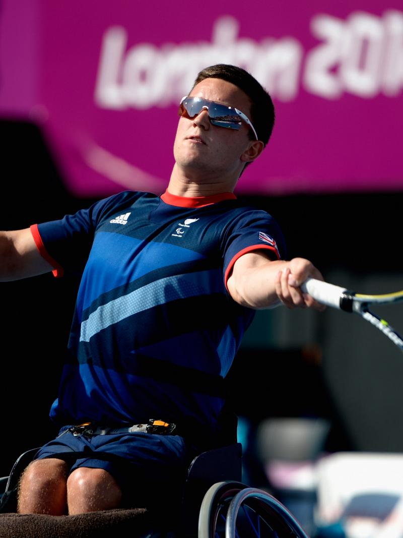 A picture of a man in a wheelchair playing a forehand during a wheelchair tennis game