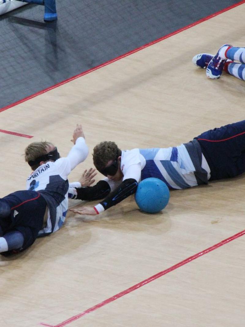 A picture of three blind men laying on the ground and trying to stop a ball