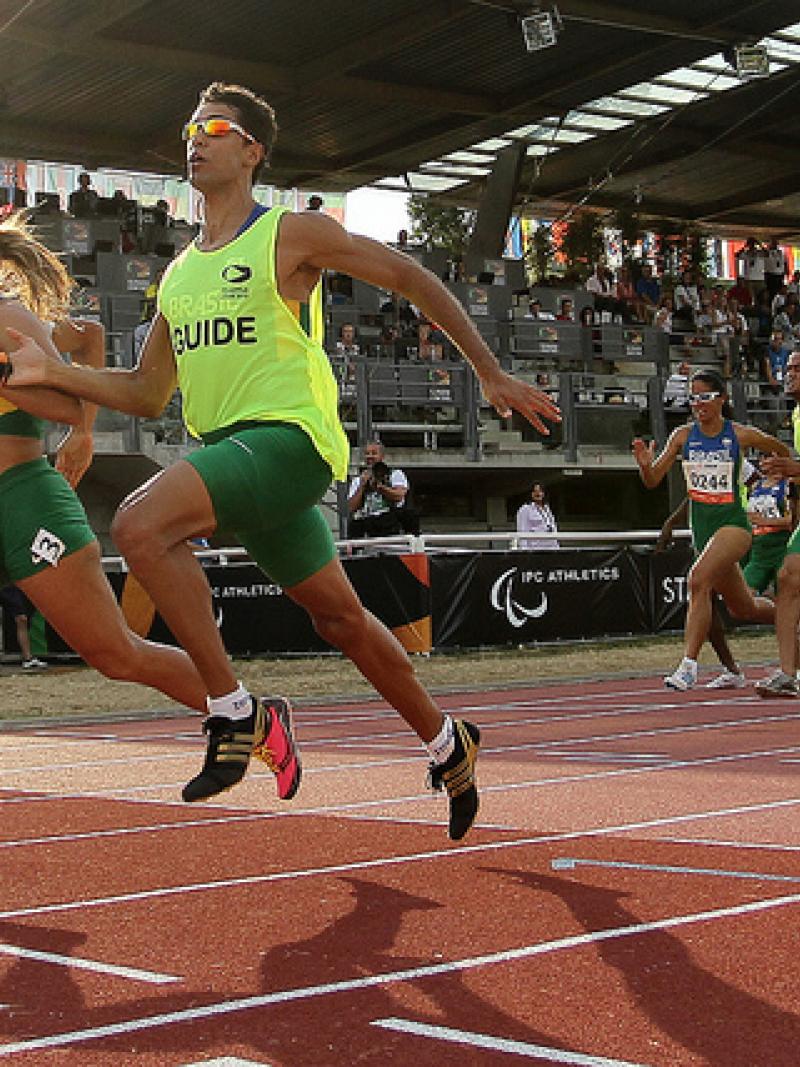 Terezinha Guilhermina and her guide run on the track of Lyon with the tribunes of the stadium in the backround