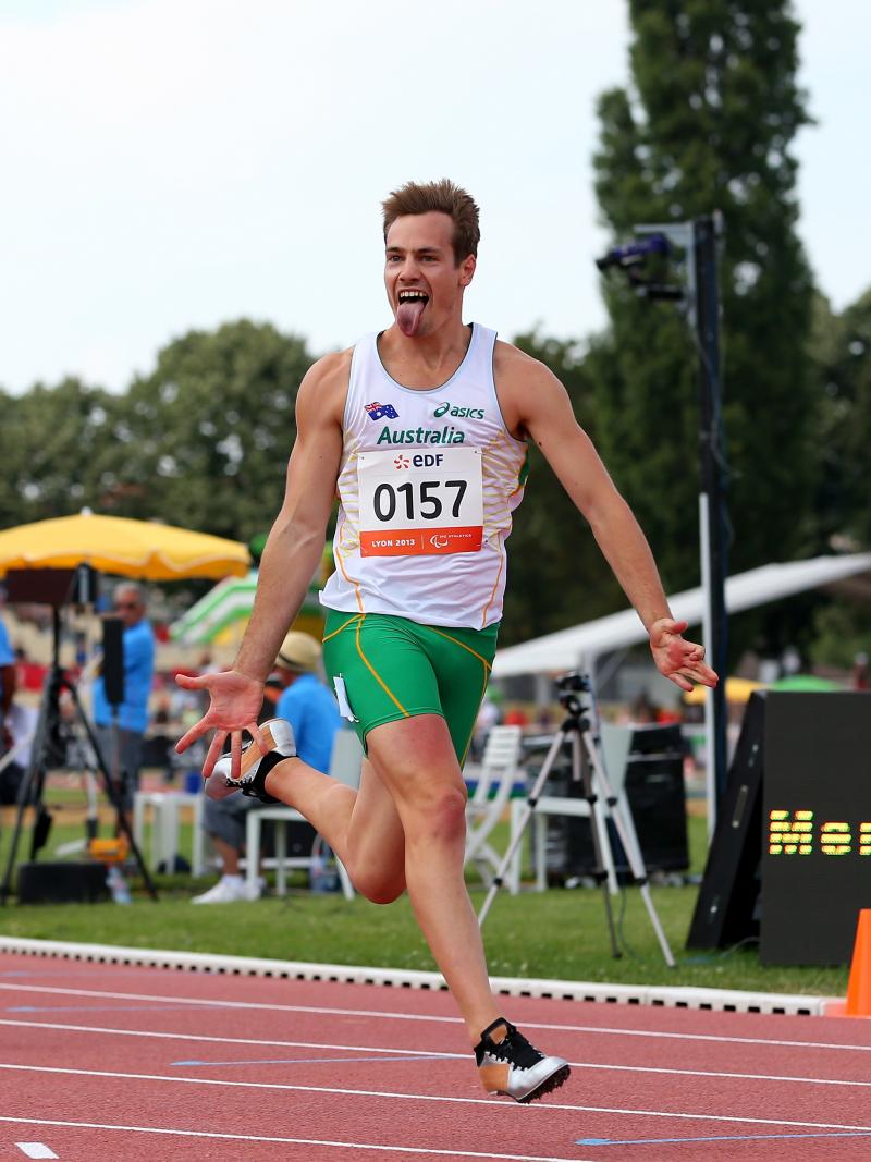 Man crossing a finish line in a stadium, celebrating