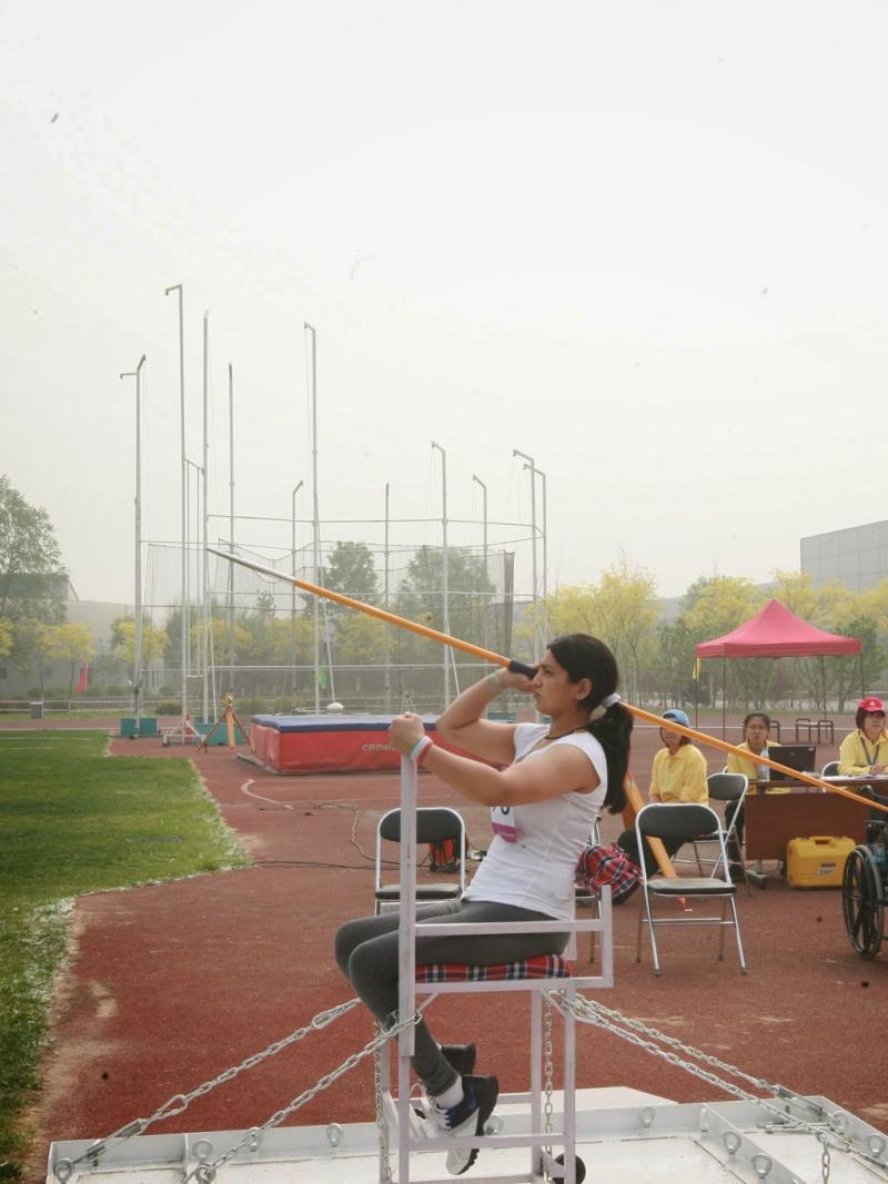 Female athlete throws the javelin from a seated position