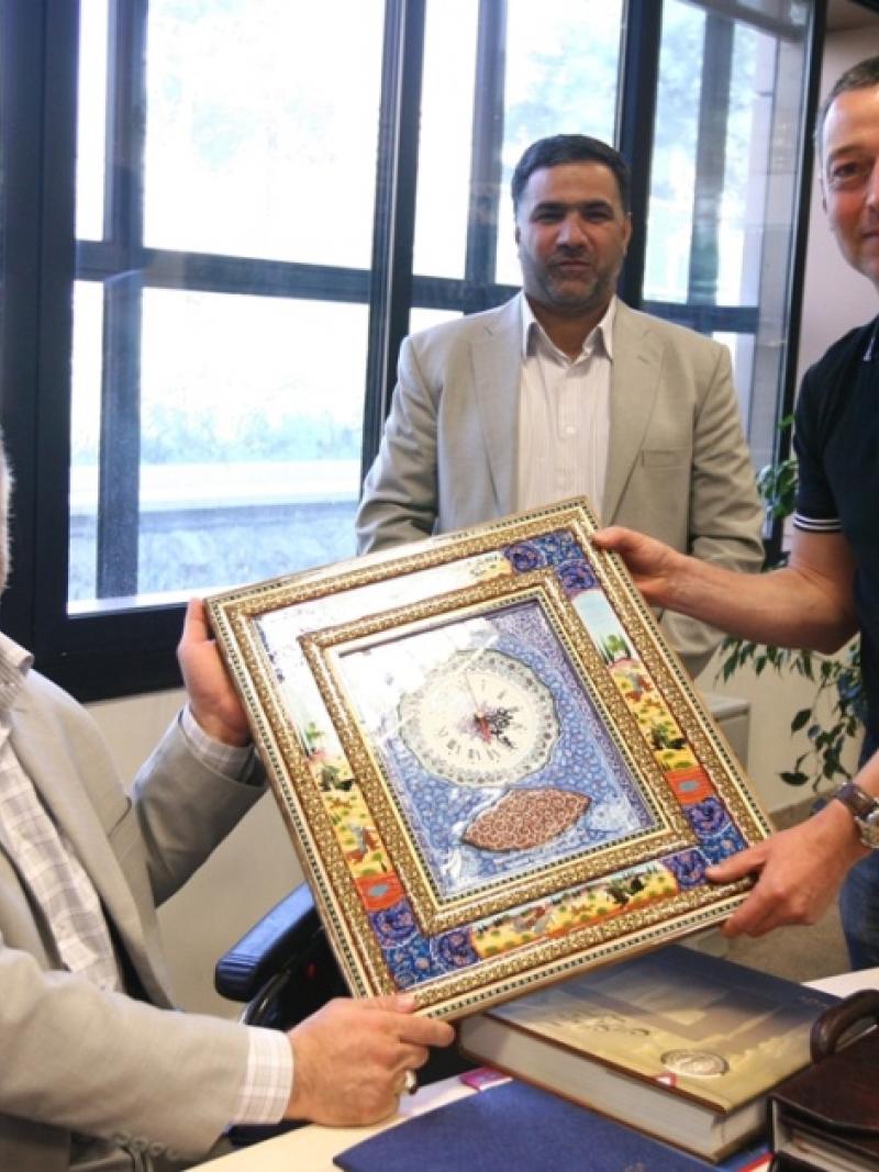 Two NPC Iran officials and reporter Ned Boulting hold up a framed award.