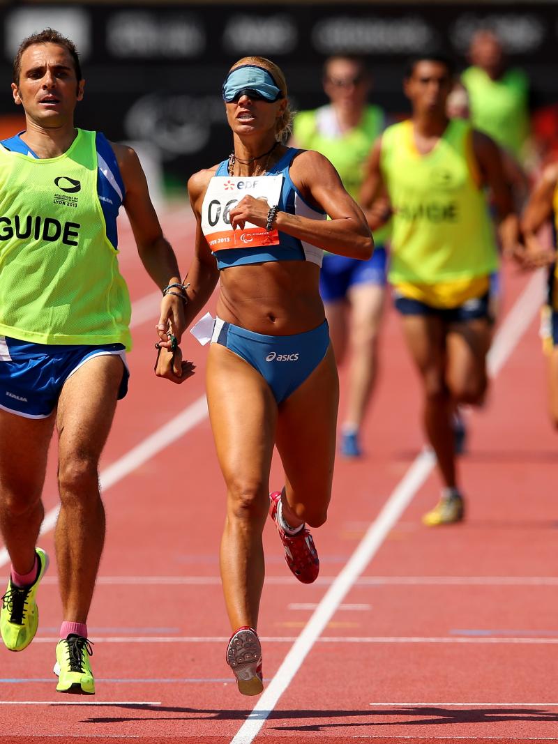 A visually impaired women and her guide running on the track of a stadium