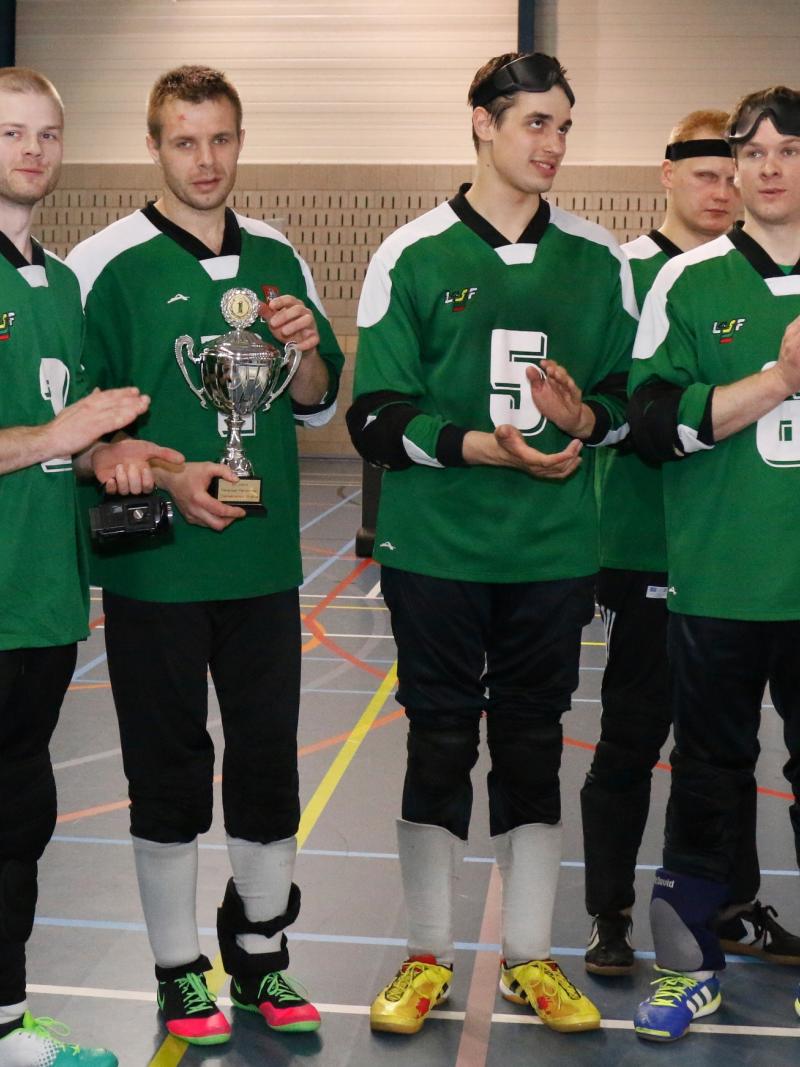 A goalball team faces the camera with their tournament trophy.