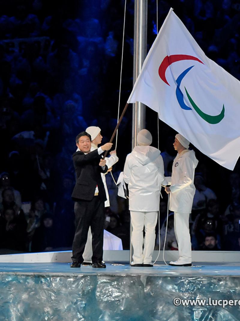 A man waves the Paralympic flag on stage