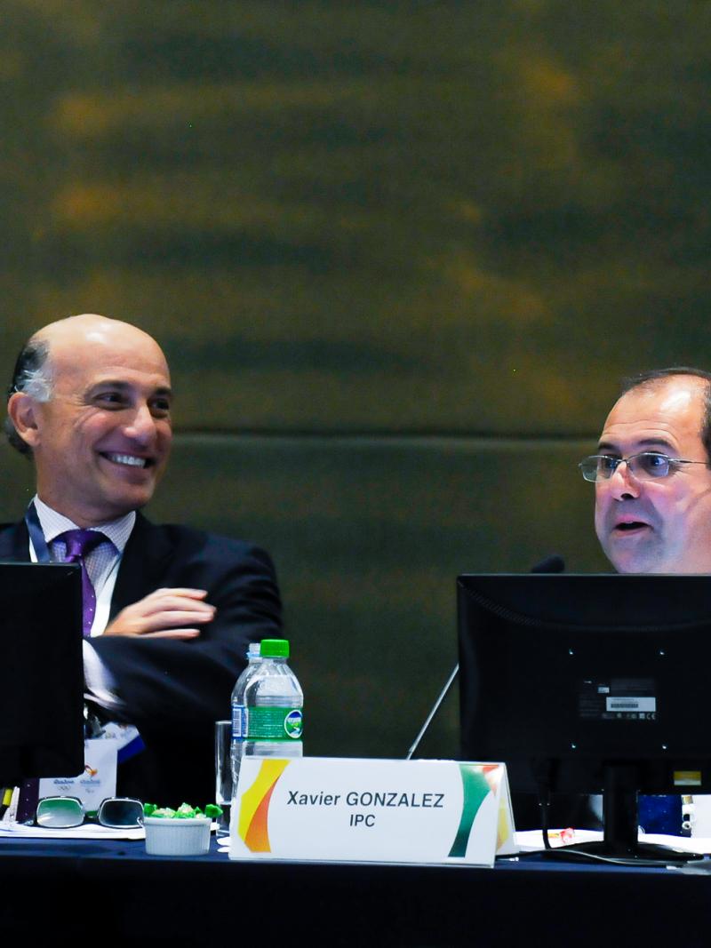 Picture of IPC Chief Executive Xavier Gonzalez and his Rio 2016 counterpart Sidney Levy dressed in suits seated behind two microphones on a table in a formal meeting.