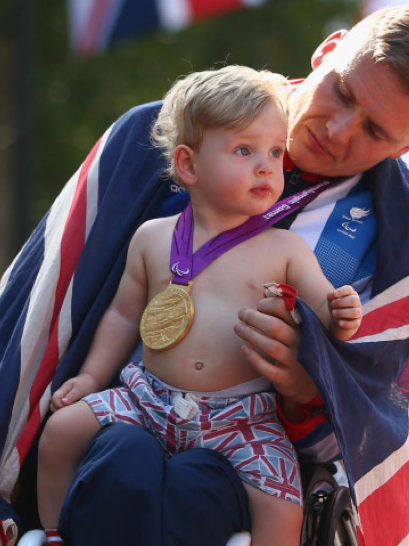 A picture of man in a wheelchair holding his baby after his victory