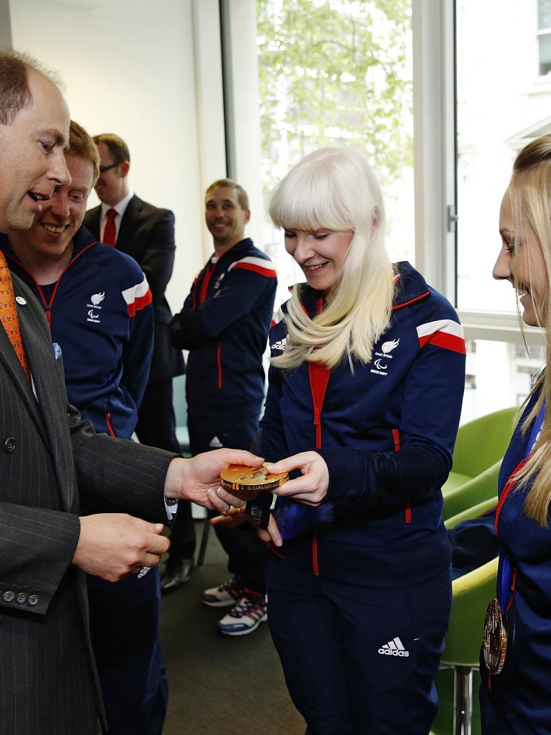 A man reaches out to look at Kelly Gallagher's Sochi 2014 gold medal.