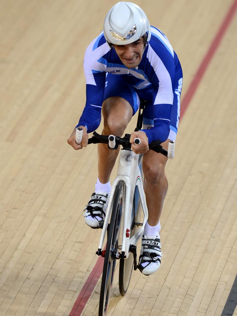 A man cycles straight ahead on a track.