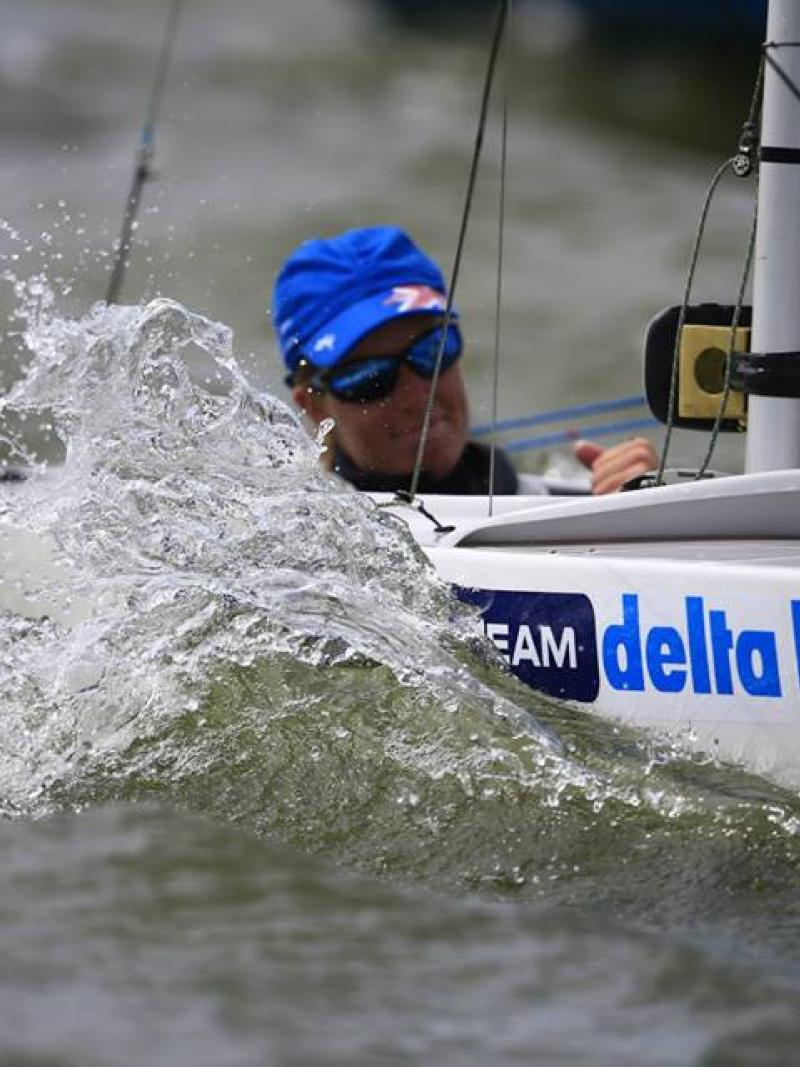 Water splashes up as a woman sails in a boat.