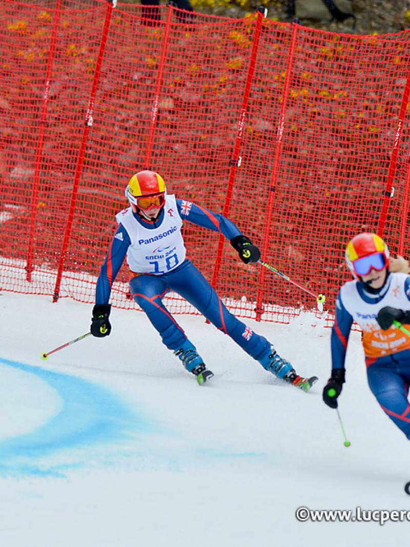 Two skiers in race suits going down a slope