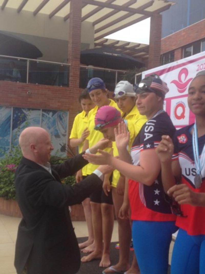 Man in black suit putting a medal around a young girls neck
