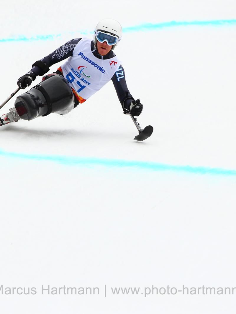 Sit skier going down a slope leans to his left