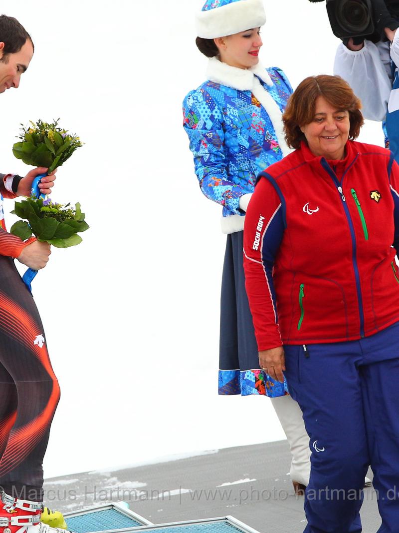 Two skiers on a podium with a women presenting them their medals