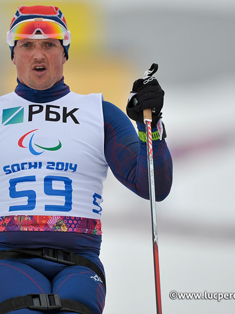 Close up of torso of sit skier driving forward through the snow with ski poles