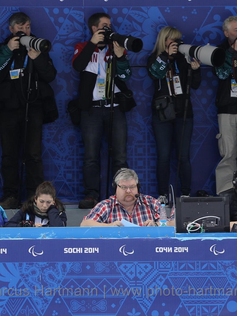A row of sport photographers taking pictures of ice sledge hockey at Sochi 2014.
