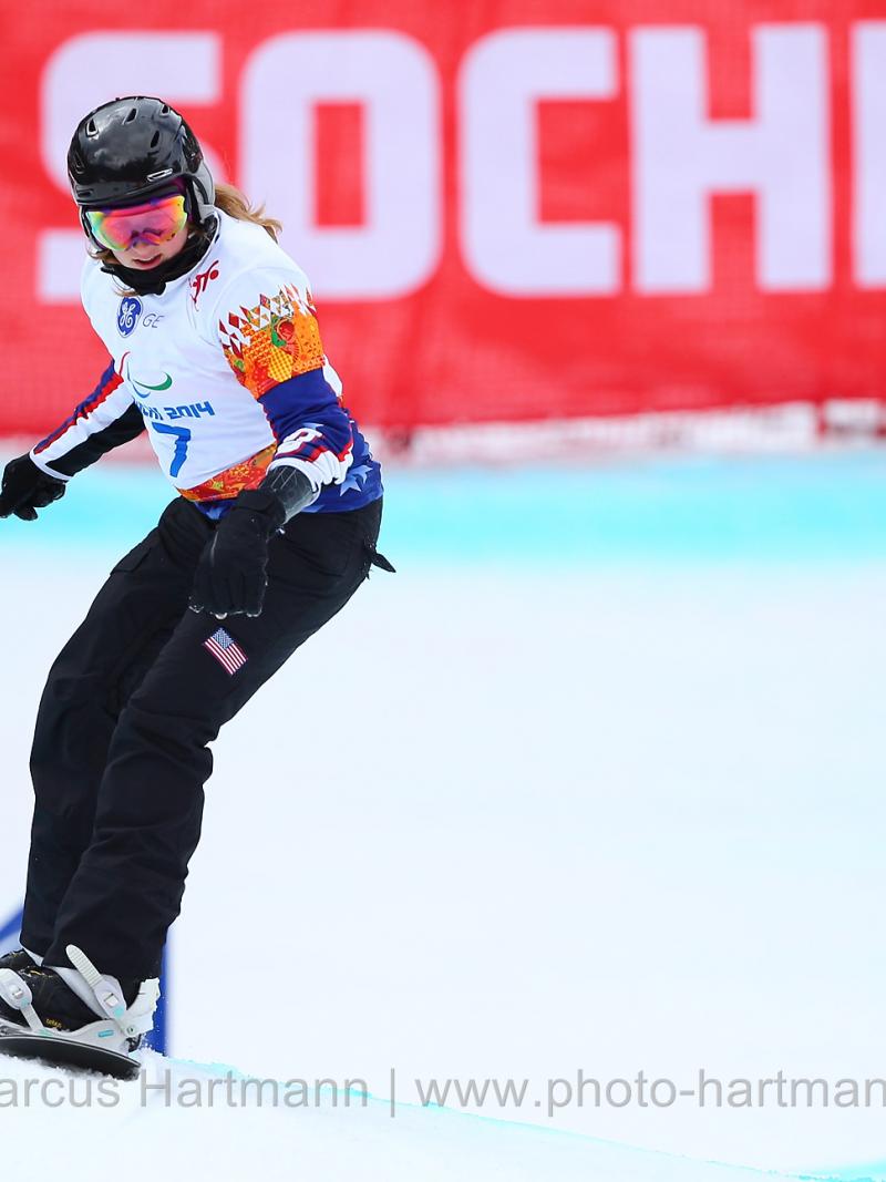 Snowboarder Nicole Roundy rides down course with Sochi 2014 banner in background