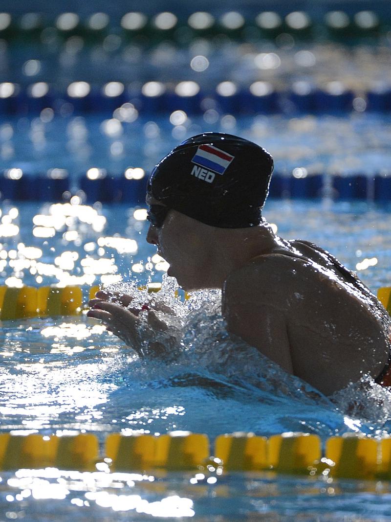 Women with black swim cap swimming breast stroke. Her head is out of the water as she is taking a breath