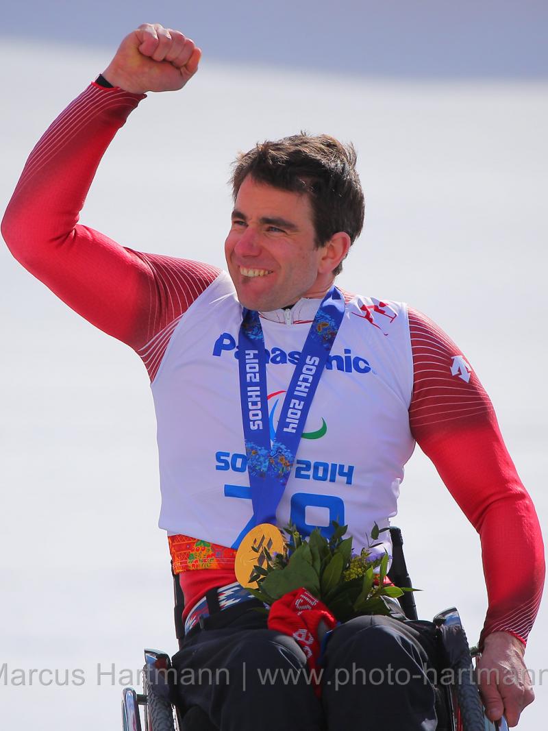 Upper body of man in wheelchair celebrating with medal around his neck