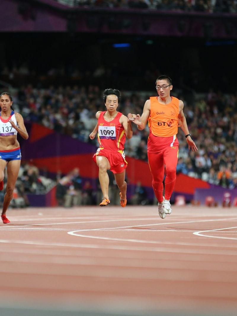 Female runners with guides on a track running