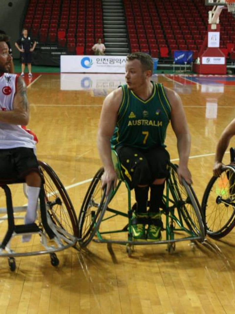 Three wheelchair basketball players fight for the ball