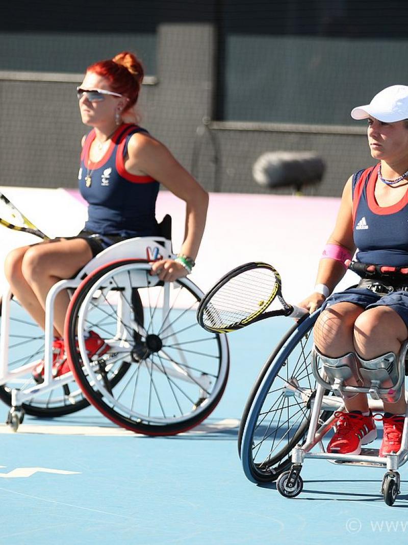 Two women in wheelchairs with tennis rackets during a match