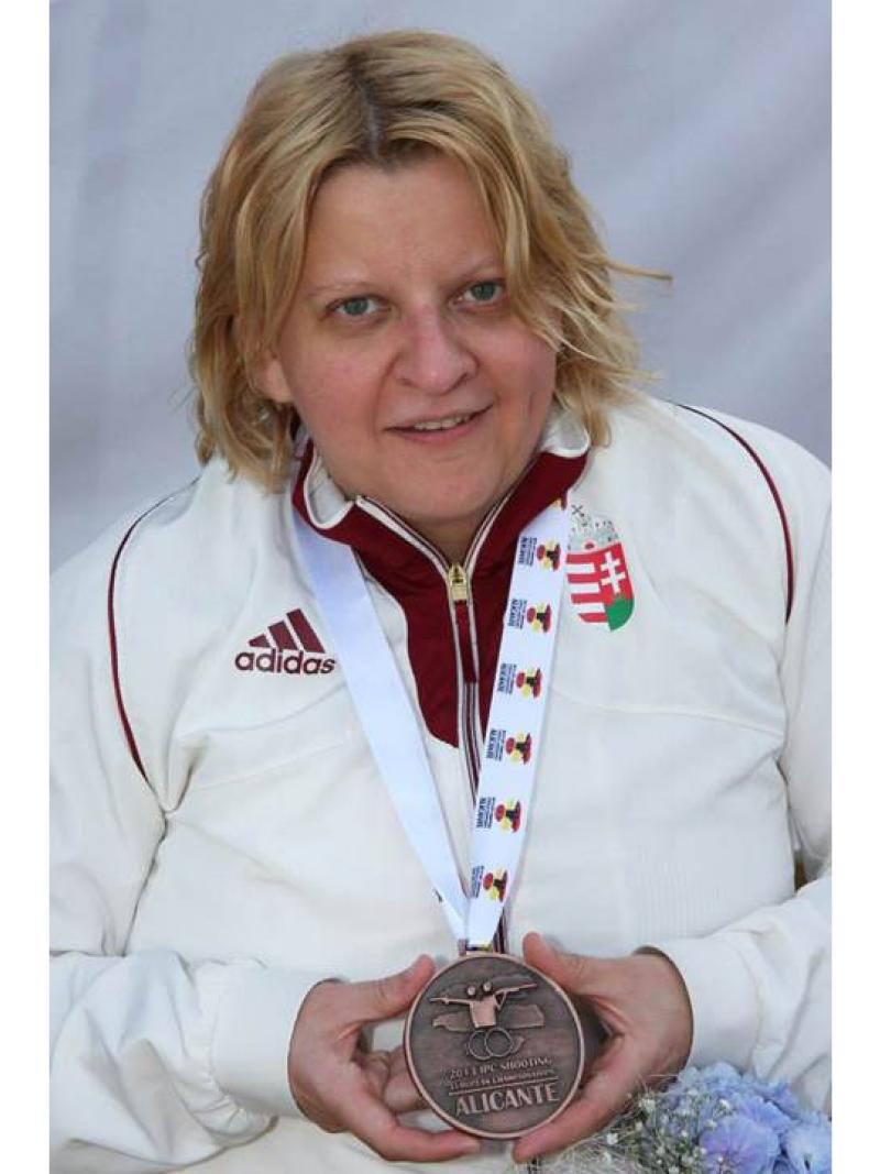 Upper body of women showing a medal to the camera