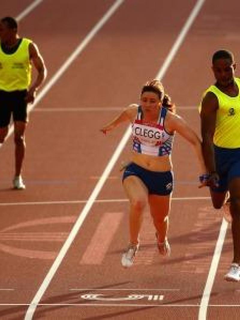 Two runners cross the finish line in a stadium